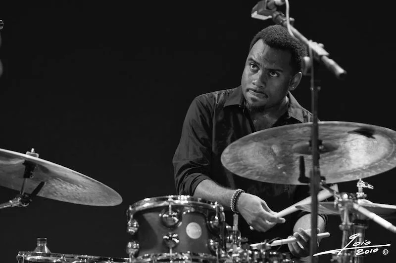 Nate Smith at his drum set looking intense. Black and white photo.