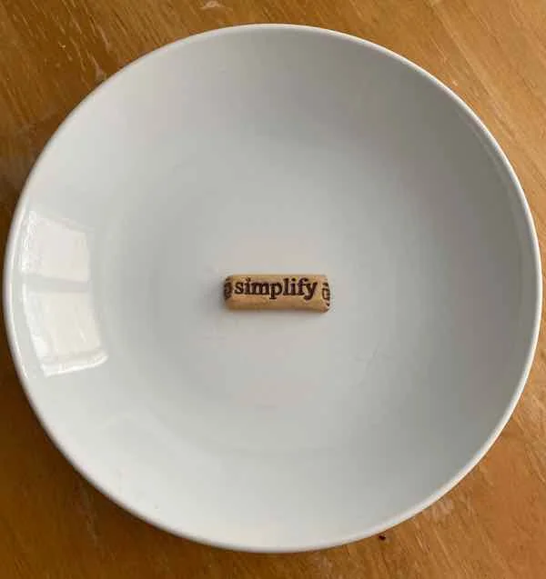A large white bowl containing an artificial stone imprinted with the word Simplify.