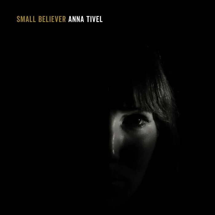 Album cover for Small Believer. Black with Anna Tivel's face in half shadow.