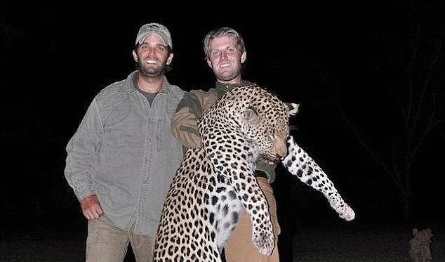 Donald Trump, Jr. and his brother Eric stand outdoors at night, smiling, holding a large leopard they hunted. The scene conveys a tone of triumph and accomplishment.